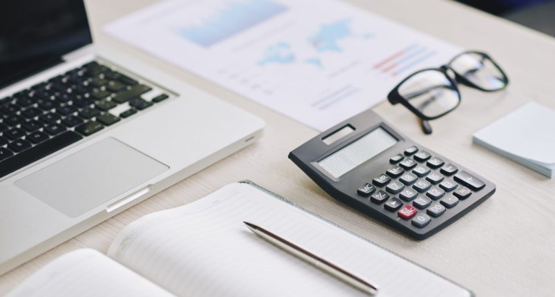Table of financial manager Calculator, laptop and financial report on office table
